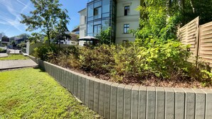 A modern building with a glass facade, a grassy area with a low stone wall, and a wooden fence.