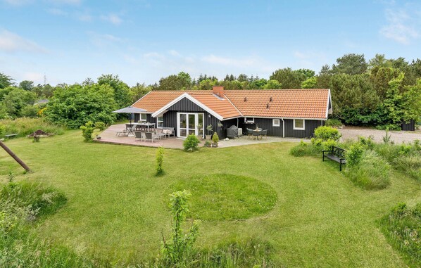 A modern house with a patio, a covered outdoor seating area, and a large lawn.