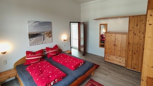 Una habitación con cama, armario, espejo y puerta que da a otra estancia.