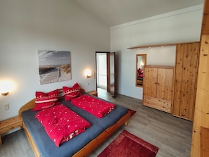 A room with a bed, a wardrobe, a mirror, and a door leading to another room. - (35) 2-room apartment - apartment house Sanssouci (Kühlungsborn)