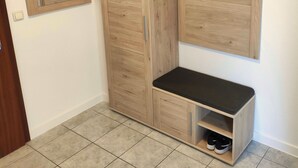 Un armario de madera con un banco, un estante pequeño y espacio para colgar.