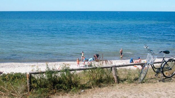 A beach with a bicycle parked near the water's edge.