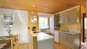 A modern kitchen with wooden cabinets, a central island, and a dining area with a table and chairs.