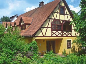 Una casa tradizionale a graticcio con tetto spiovente, un ingresso principale e un piccolo giardino.