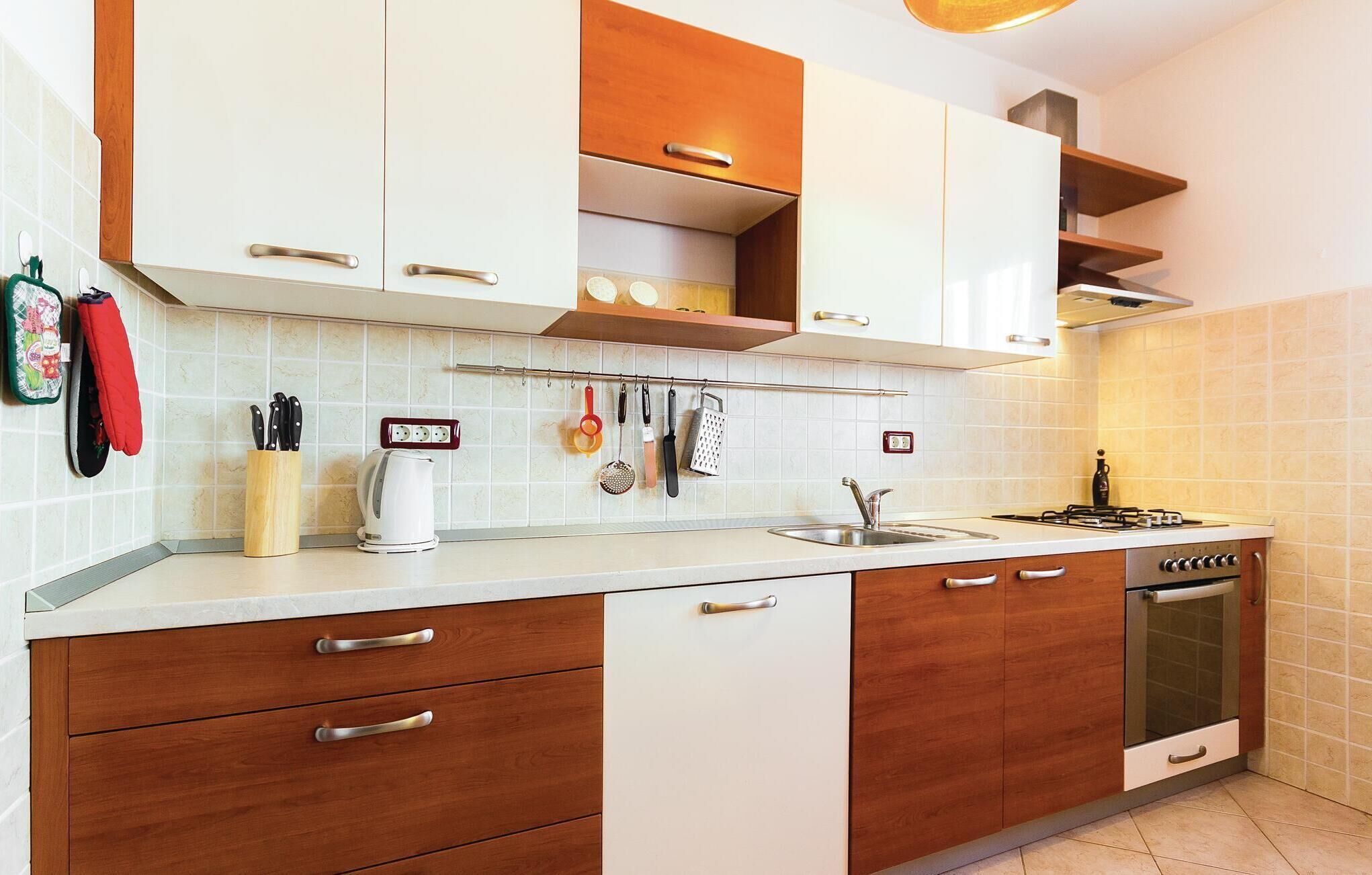 Una cocina moderna con armarios blancos, encimeras de madera y horno empotrado.