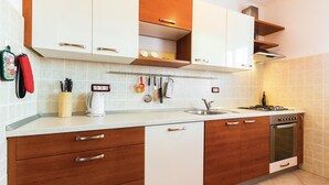 Een moderne keuken met witte kasten, houten aanrecht en een inbouwoven.