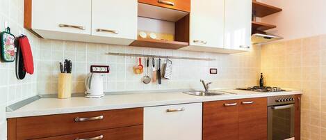 Una cocina moderna con armarios blancos, encimeras de madera y horno empotrado.