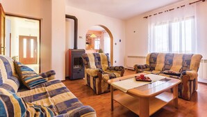 Een woonkamer met een bank, fauteuils, een salontafel en een open haard.