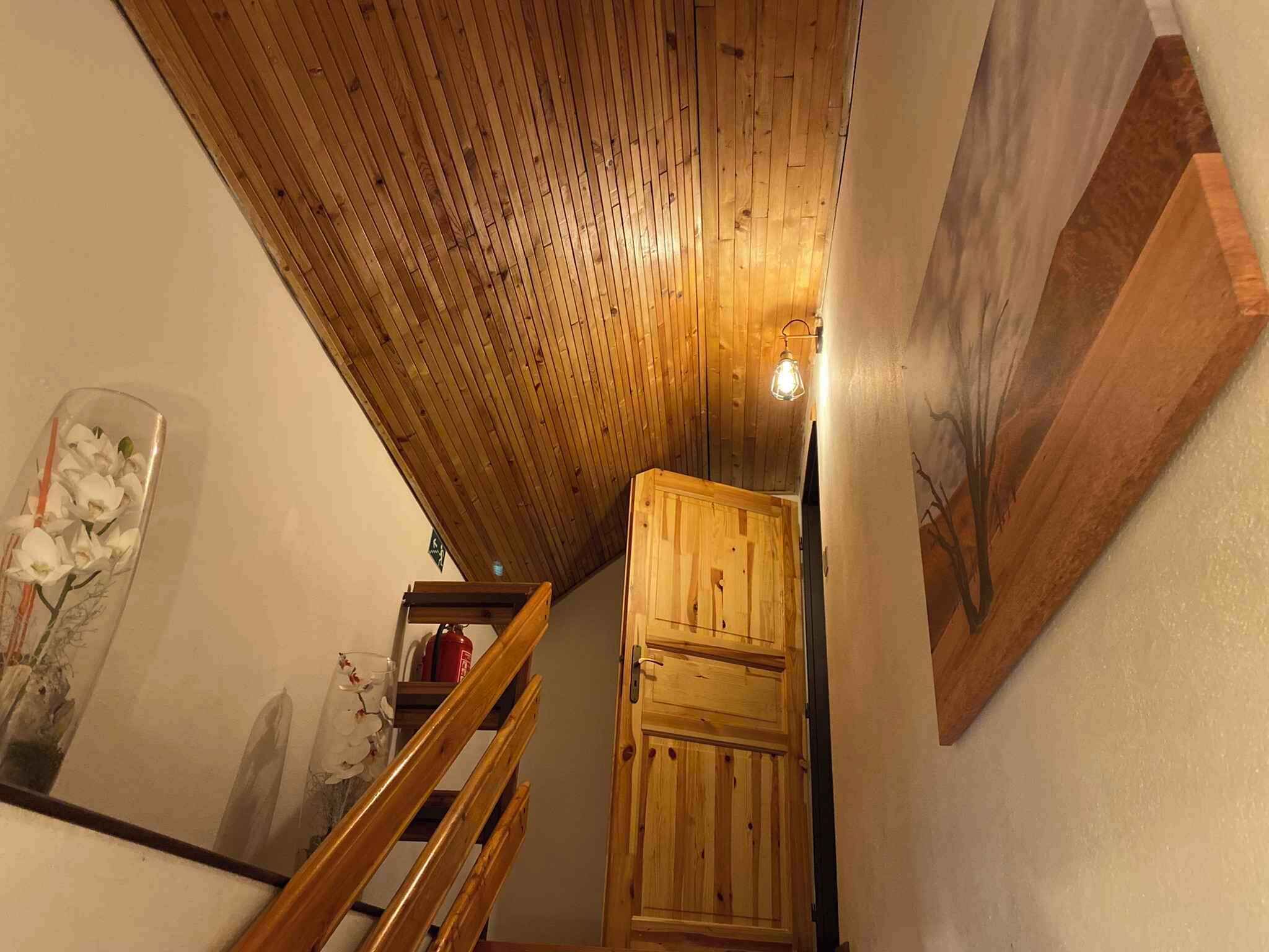 Una escalera de madera que lleva a un altillo con techo inclinado y una puerta de madera.