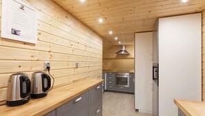 Une cuisine moderne avec un lambris en bois, des appareils électroménagers en acier inoxydable et des meubles de couleur grise.