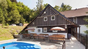 Un chalet traditionnel doté d’une piscine, d’un espace extérieur aménagé et surplombant une forêt.