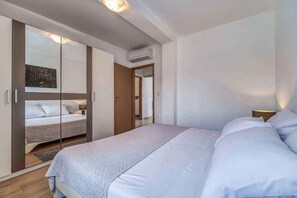 A bedroom with a bed, a wardrobe, and a mirror. - Holiday apartment with air conditioning (Porat)