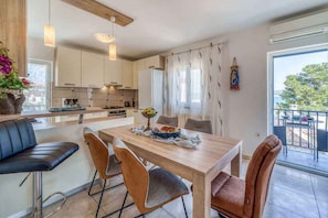 A modern kitchen with a dining area, bar seating, and a view to the outside. - Holiday apartment with air conditioning (Porat)