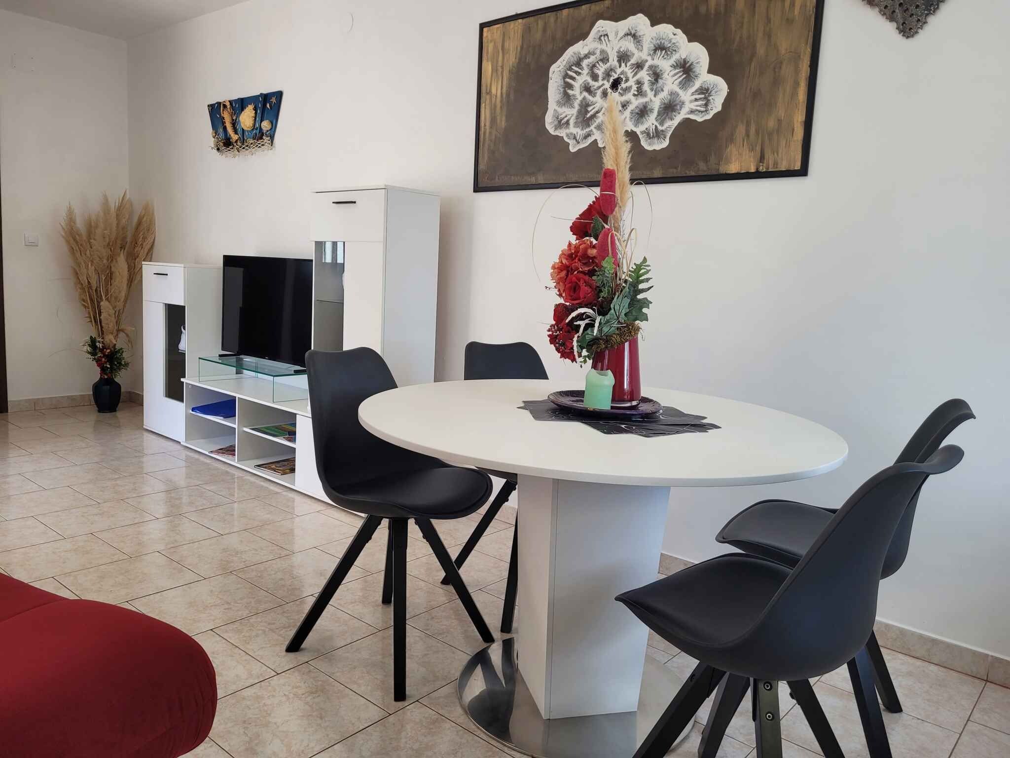 A modern dining area with a round table, black chairs, and a red sofa.