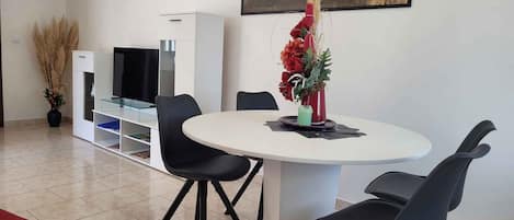 A modern dining area with a round table, black chairs, and a red sofa.