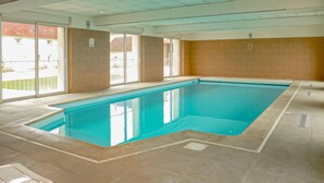 An indoor swimming pool with clear glass walls, a tiled floor, and a view of buildings outside. - Lovely home in Vaudoy-en-Brie with WiFi (Vaudoy-en-Brie)