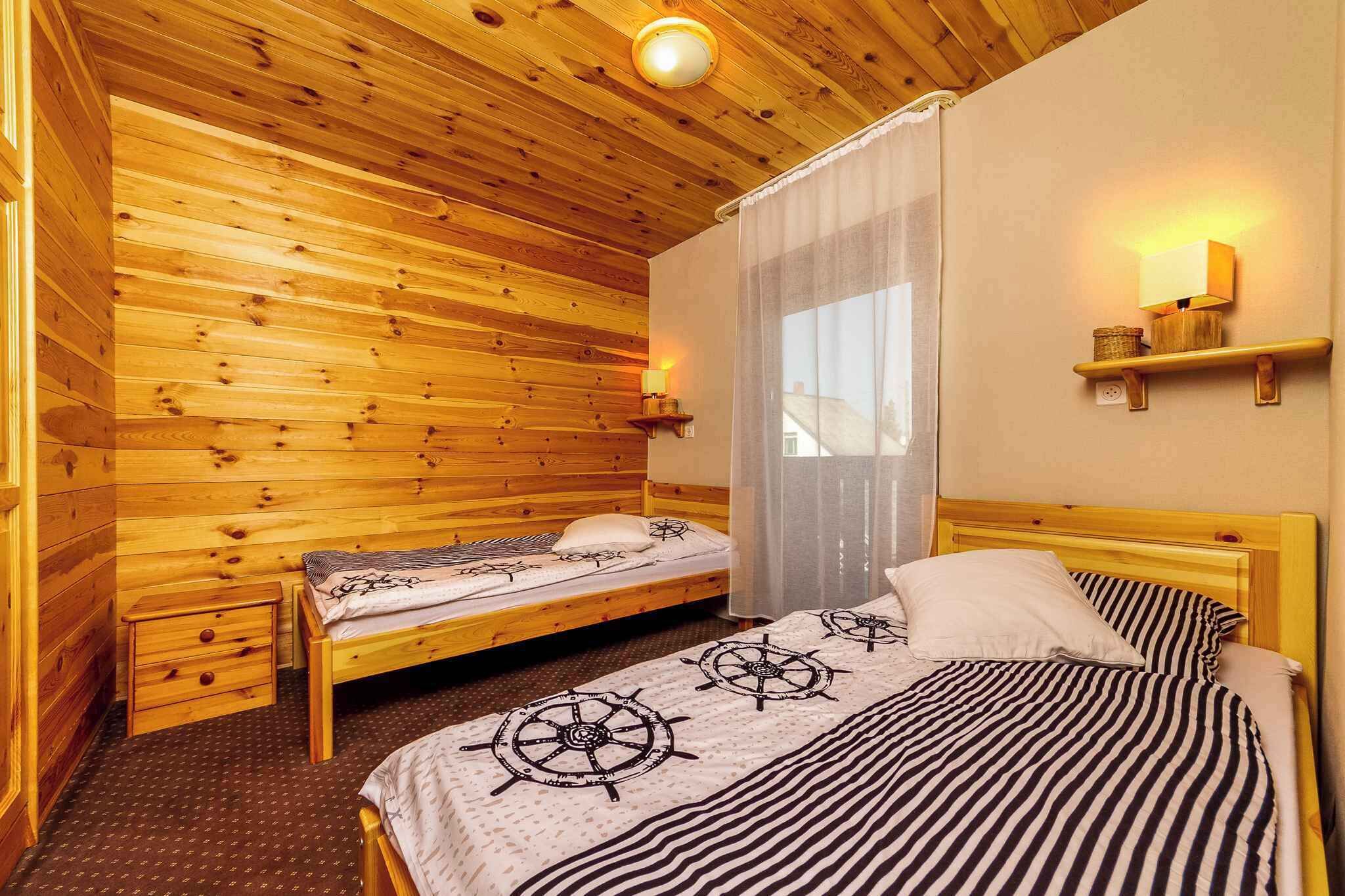 Une pièce de style cabane en bois, avec deux lits, une fenêtre avec des rideaux, une étagère fixée au mur et un luminaire au plafond.