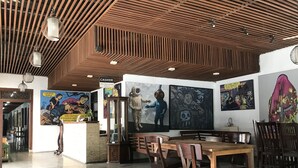 Restaurante com teto de madeira, chão de azulejos e diversas obras de arte nas paredes.