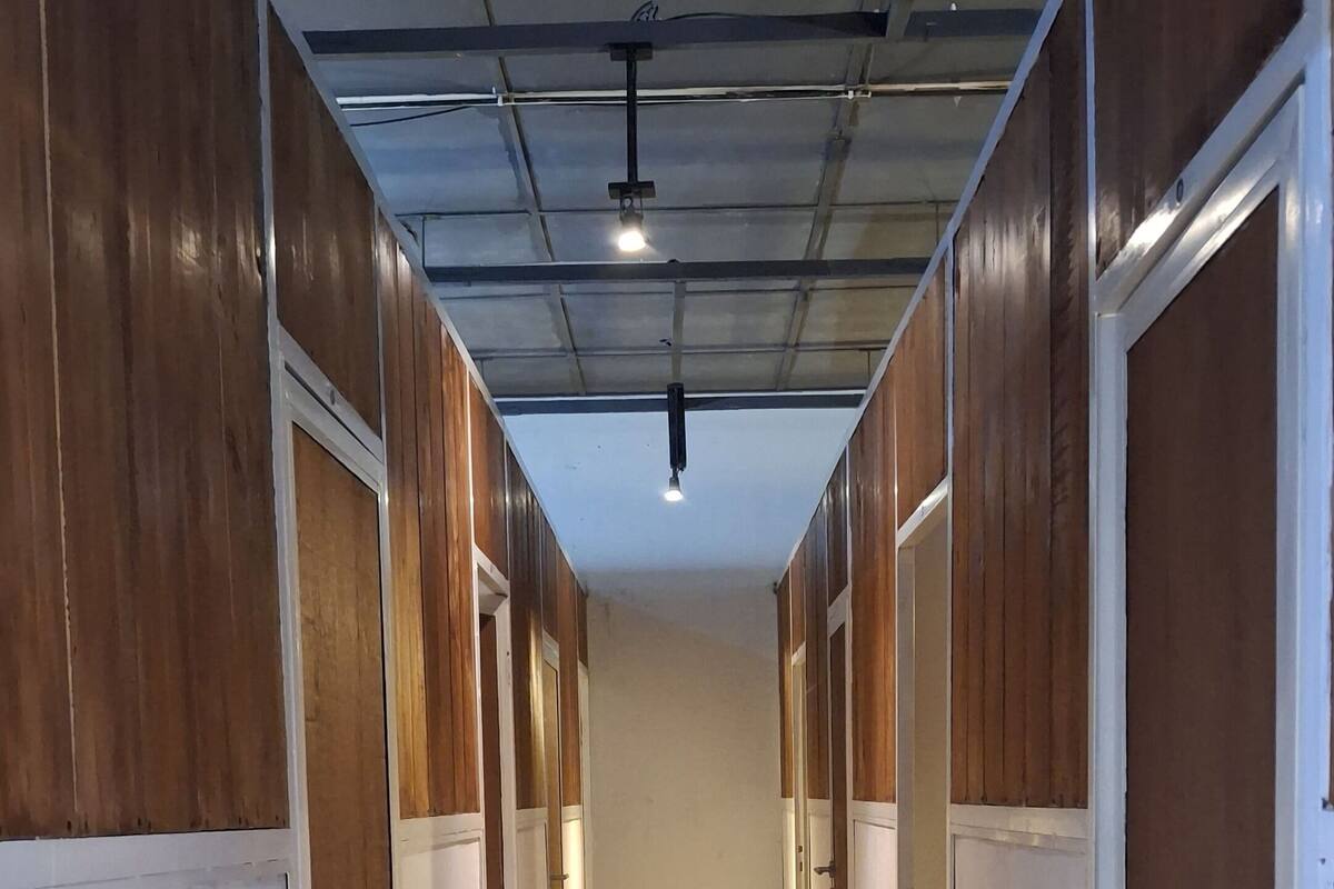 A long, narrow hallway with wooden paneling on the walls and white doors.