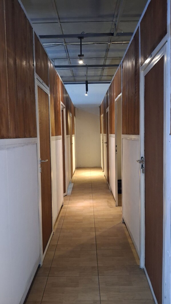 Un pasillo largo y estrecho con paneles de madera en las paredes y puertas blancas.