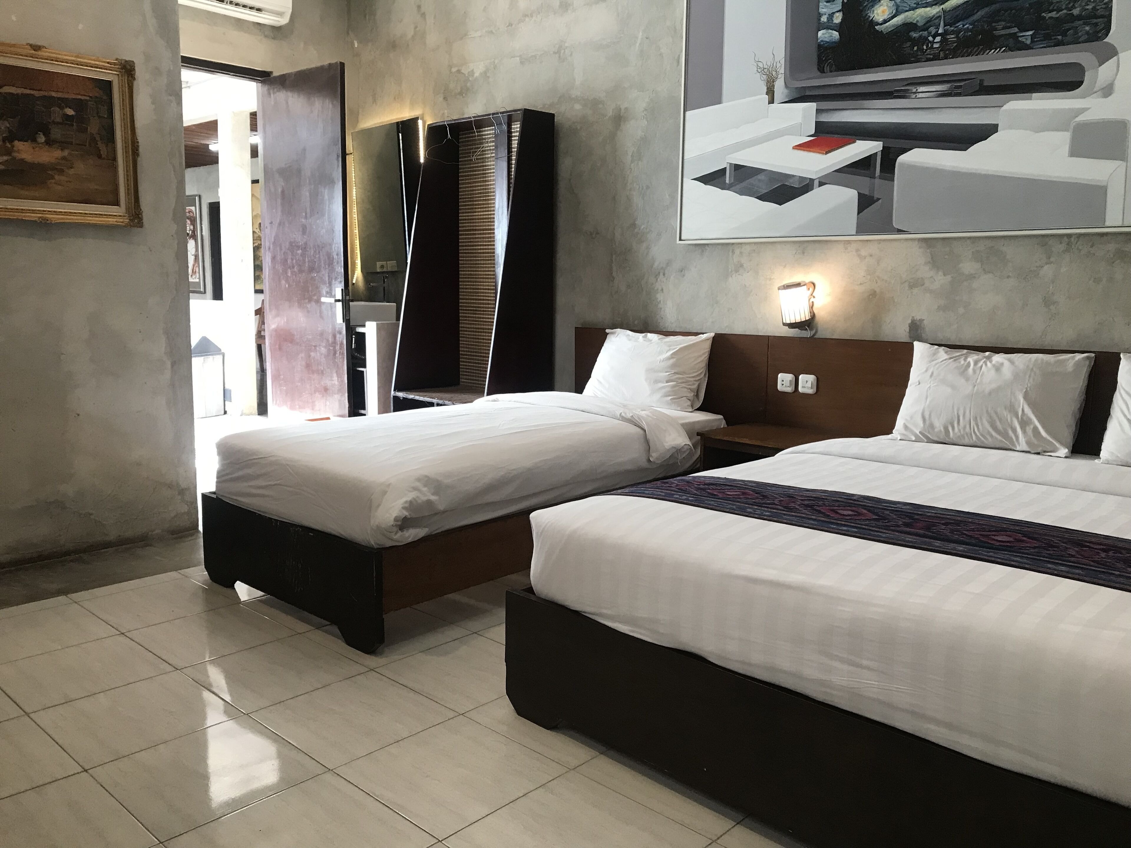 A hotel room with two beds, a TV, a painting, and a large window.