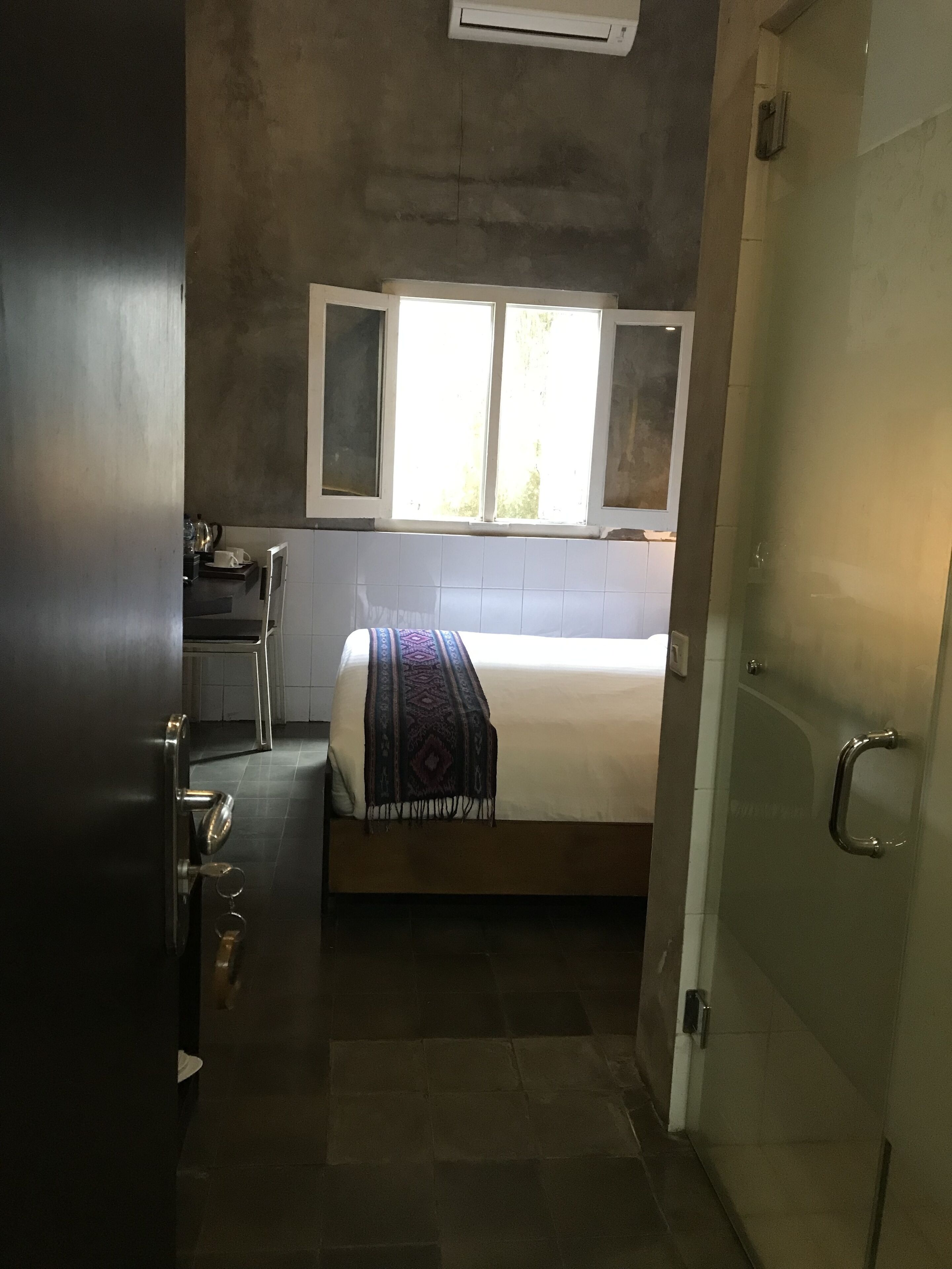 Una habitación compacta con cama, ventana y kitchenette.