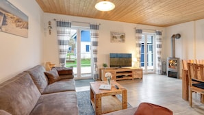 Een gezellige woonkamer met een houten plafond, een bank, een salontafel, een televisie en een open haard.