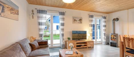 Ein gemütliches Wohnzimmer mit Holzboden, einer Couch, einem Couchtisch, einem Fernseher und einem Kamin.