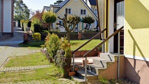 Un barrio residencial con una casa que tiene una escalera que lleva a la entrada, un camino de entrada pavimentado y un césped cuidado.