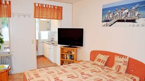 Un dormitorio con cama, televisión, estantería y vistas a la playa y al muelle.