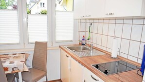 Una cocina con un lavamanos, una silla y una mesa.