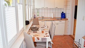 Una cocina compacta con armarios blancos, un lavamanos y una zona de comedor con una mesa y sillas.