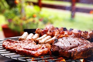 Un barbecue avec différentes sortes de viandes et de saucisses en train de cuire à l’extérieur.
