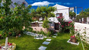 A white house with a garden, a pergola, and a stone pathway.