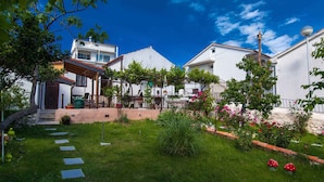 A residential area with a well-maintained garden, paved pathways, and white buildings.