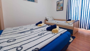 A hotel room with a bed, a bench, and two paintings on the wall.