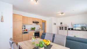 Ett modernt kök med träskåp, ett matbord med stolar, en soffa och en tv.