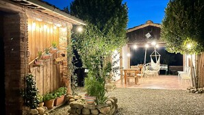 An outdoor patio area with stone walls, wooden furniture, and string lights. - Cozy apartment in S.Martino in Colle LU with swimming pool (S.Martino in Colle LU)