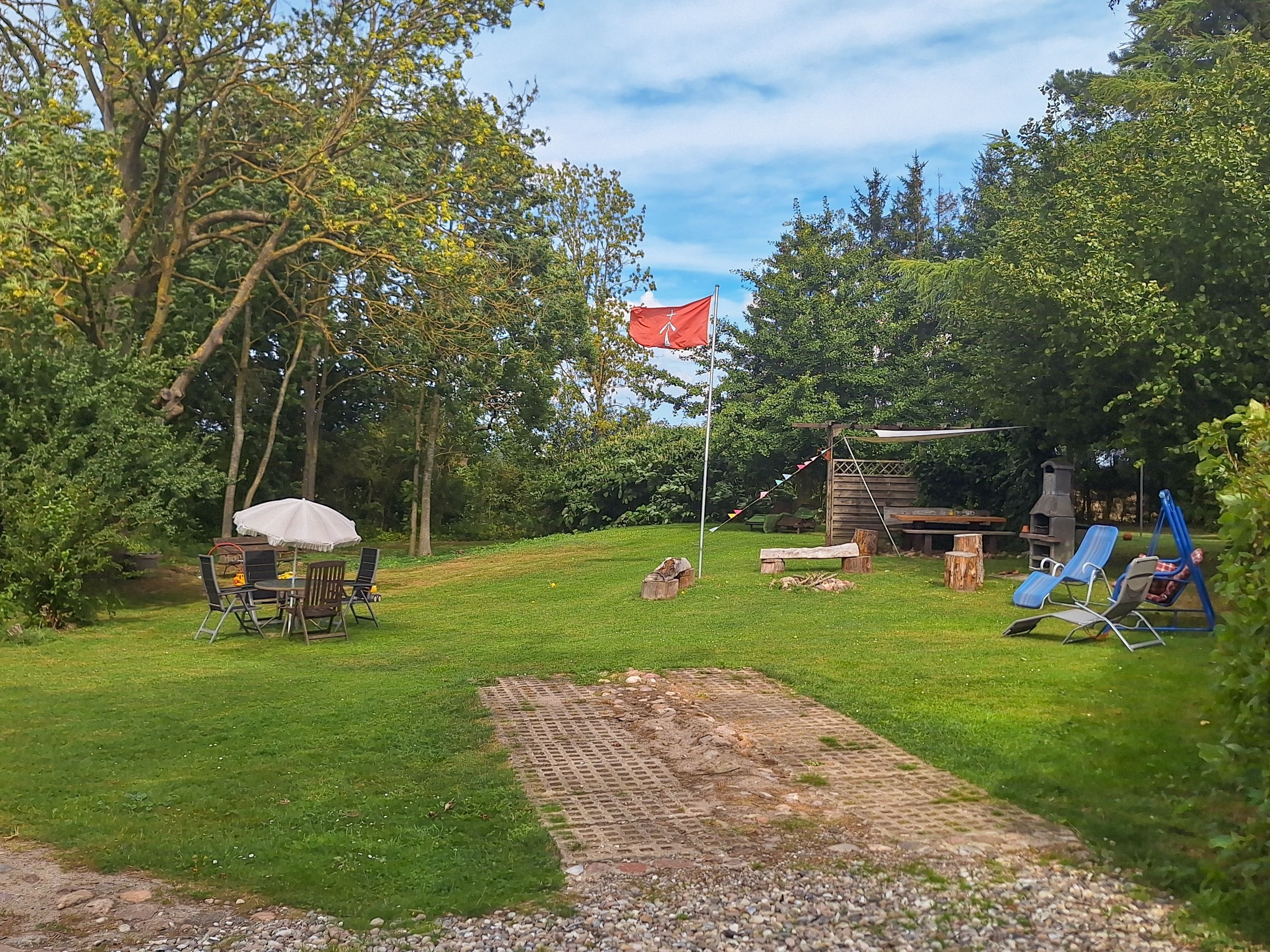 A backyard with a barbecue area, outdoor seating, and a flagpole.