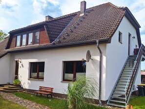 A two-story house with a tiled roof, a satellite dish, and a staircase leading to the upper floor. - Vacation apartment 2 - Holiday apartments on the edge of the forest (Ahrenshagen-Daskow)