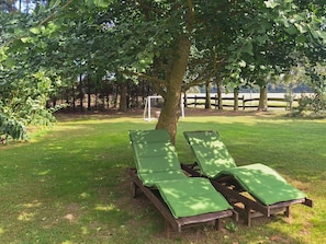 A tree-lined outdoor area with wooden lounge chairs and a soccer goal in the background. - Vacation apartment 2 - Holiday apartments on the edge of the forest (Ahrenshagen-Daskow)
