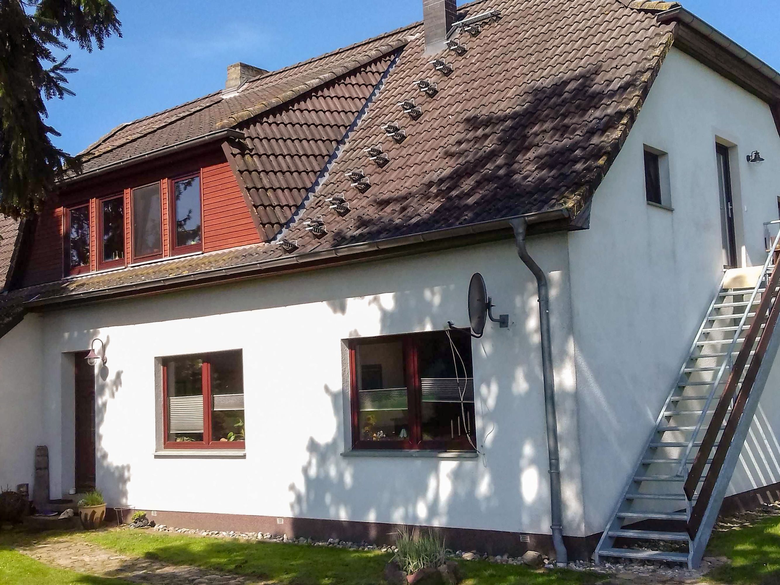 A two-story house with a sloped roof, a satellite dish, and a visible staircase leading to the upper floor.