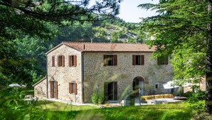 Un bâtiment en pierre avec un toit en tuiles, de nombreuses fenêtres et un petit patio.