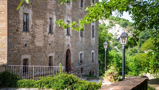 Un vieux bâtiment en pierre doté de nombreuses fenêtres et d’une arche centrale.