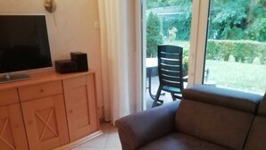 A living room with a television on a wooden cabinet, a brown sofa, and a coffee table with a decorative item. - * FeWo Hansel GM 69372 - FeWo Hansel (Graal-Müritz)