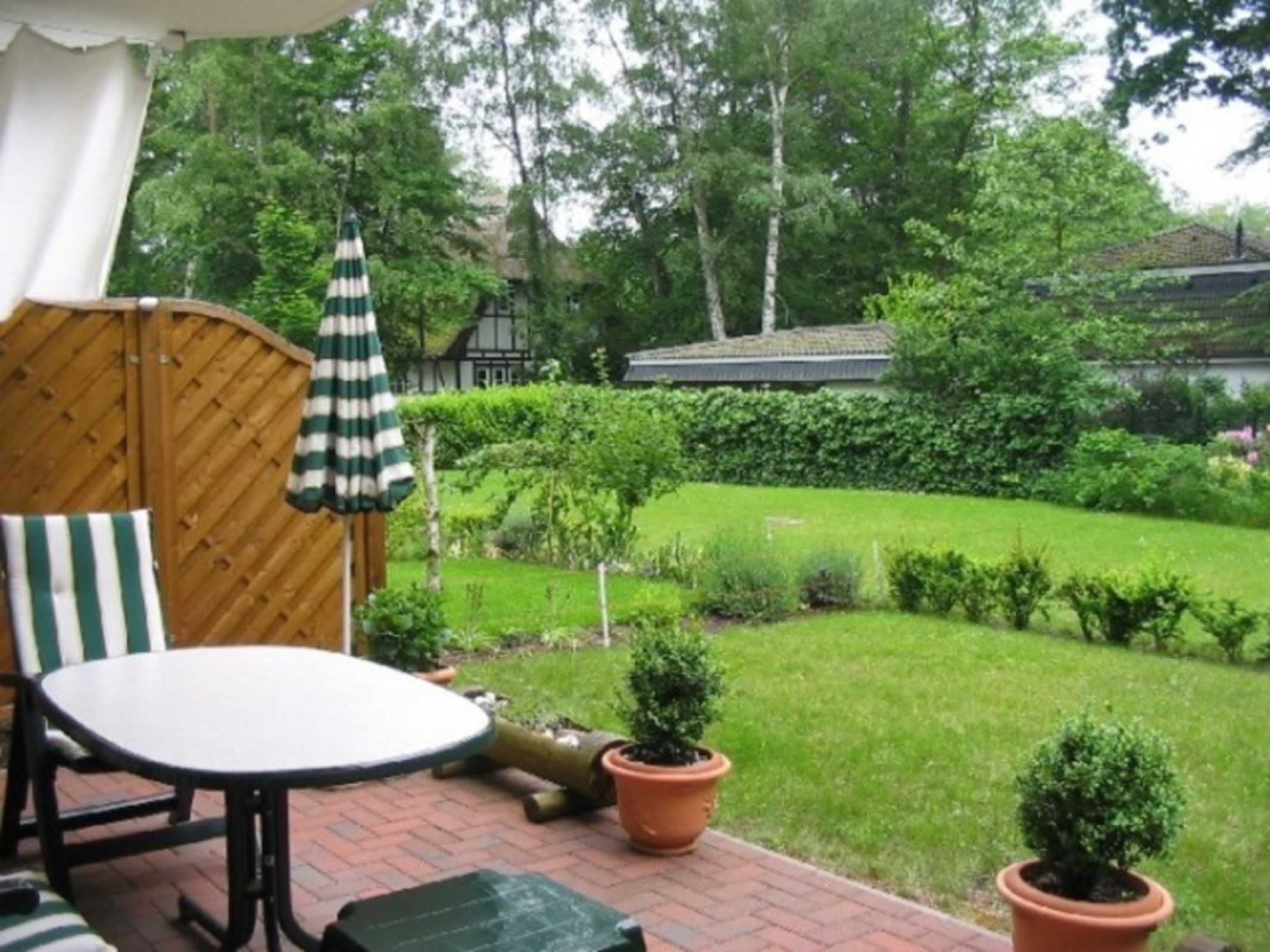 Une terrasse avec une table et des chaises, un parasol à rayures et des plantes en pot.