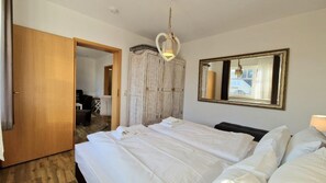 Ein Hotelzimmer mit einem großen Bett, einem Kleiderschrank, einem Spiegel und einer Hängelampe.