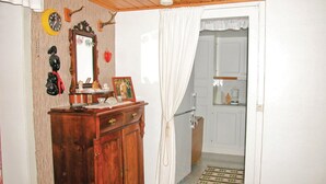 Ein Zimmer mit einem Holzkapuzenbügel, einem Spiegel, einer Uhr und einer Tür zu einem Badezimmer.