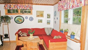Ein gemütliches Zimmer mit einer Holzsofa, einem kleinen Holztisch und einem Fenster mit Blumentöpfen.