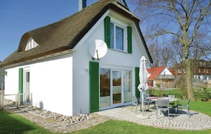 A white house with green shutters, a satellite dish, and a patio with outdoor furniture. - Beautiful home in Insel Poel/Kirchdorf (Insel Poel/Kirchdorf)